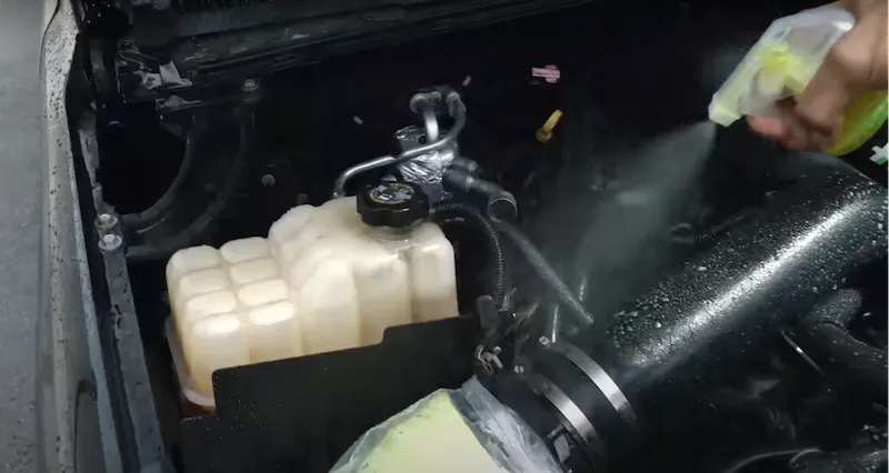 Phun dung dịch tẩy rửa chuyên dụng lên bề mặt động cơ khi vệ sinh khoang máy ô tô